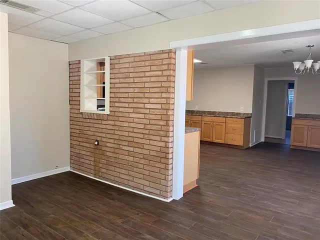 a view of a hallway with an empty room and wooden floor