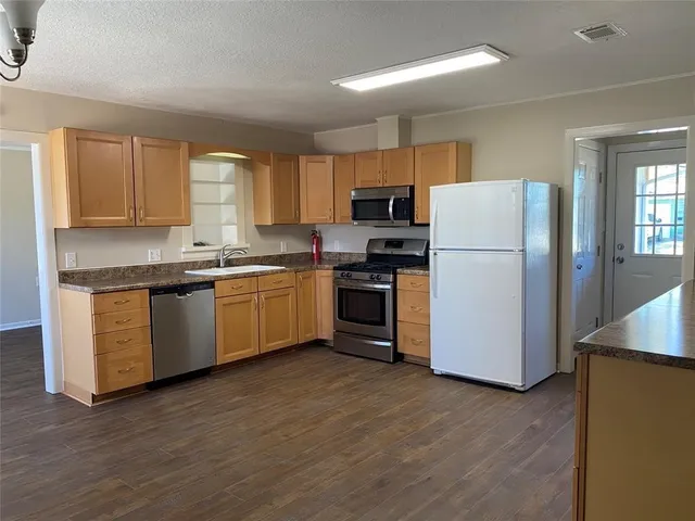 a kitchen with a sink a refrigerator a window and cabinets
