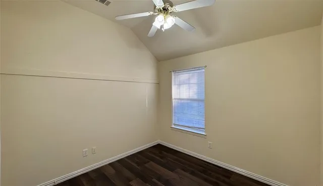 an empty room with chandelier fan and windows
