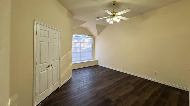 an empty room with wooden floor and fan