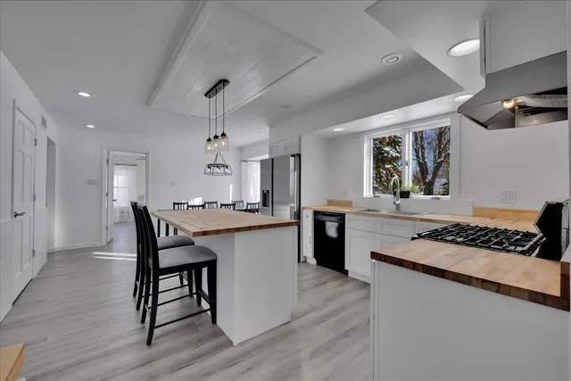 a kitchen with stainless steel appliances granite countertop a stove a sink dishwasher and a refrigerator with wooden floor