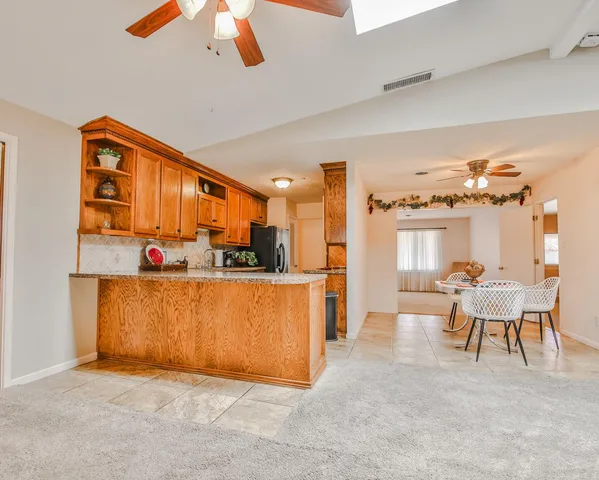 a living room with furniture a chandelier fan and a large window