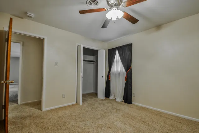 an empty room with closet and a chandelier fan