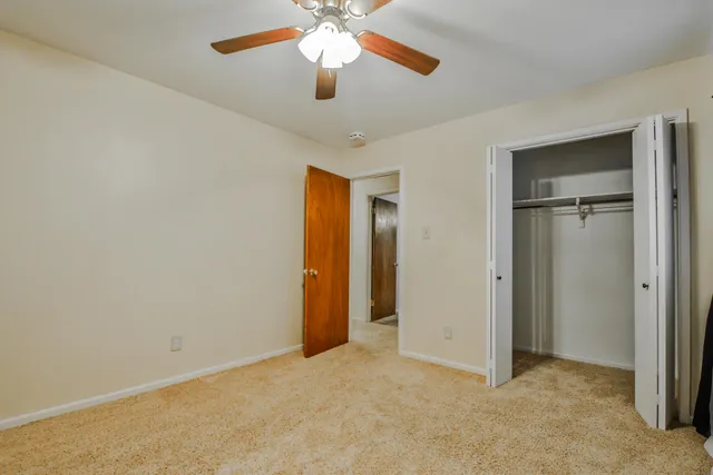 an empty room with closet and a chandelier fan