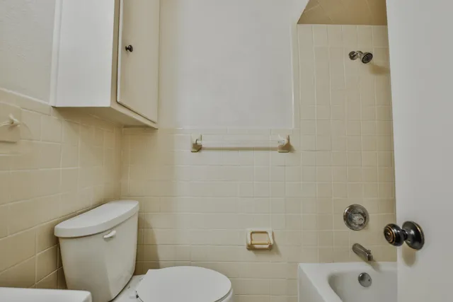 a white toilet sitting next to a bath tub