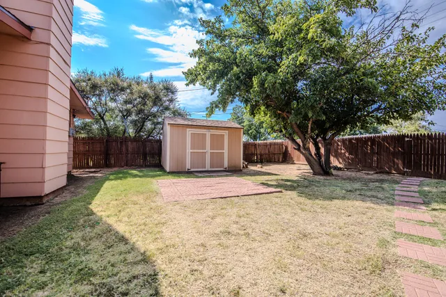 a view of a backyard with a large tree and wooden fence