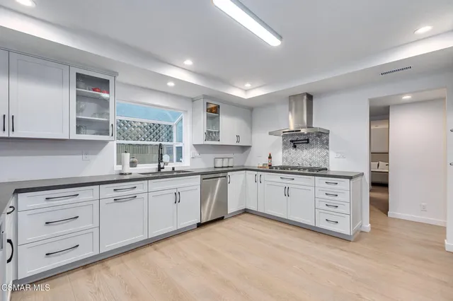 a kitchen with granite countertop stainless steel appliances a refrigerator and cabinets