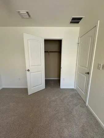 an empty room with a chandelier fan and windows