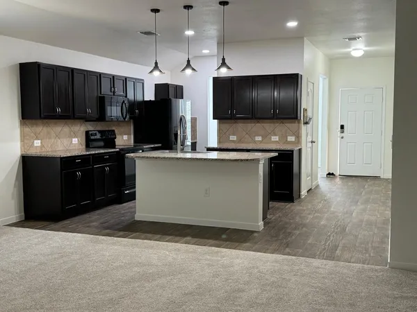 a kitchen with stainless steel appliances kitchen island granite countertop a stove and a refrigerator