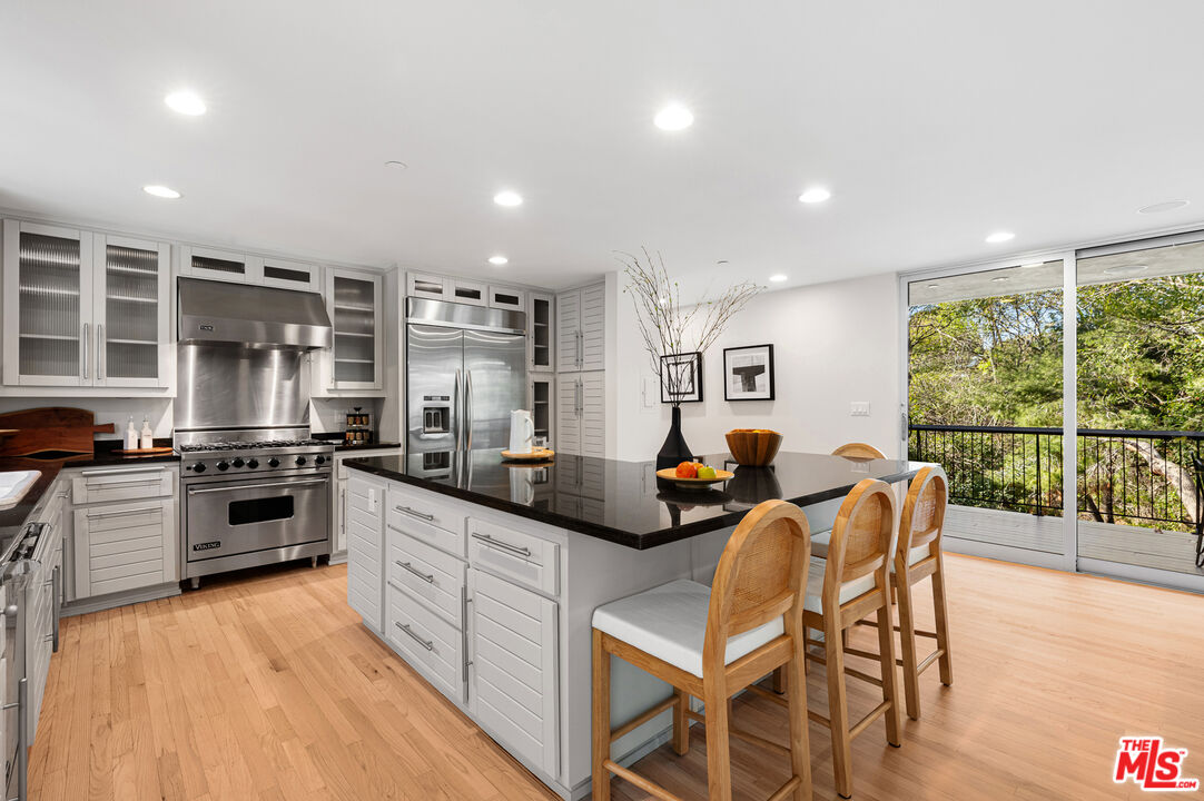 3114 Streamview Lane Studio City, CA 91604 - Photo 15 of 75 a kitchen with stainless steel appliances granite countertop a stove top oven a sink a dining table and chairs with wooden floor