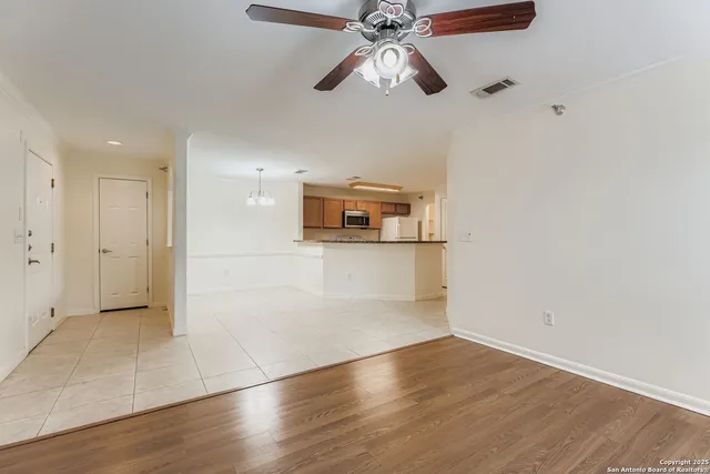 an empty room with wooden floor ceiling fan and windows
