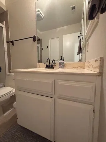 a bathroom with a granite countertop sink toilet and shower