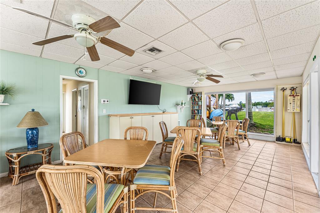 2758 Northeast 30th Avenue, Unit 3A Lighthouse Point, FL 33064 - Photo 16 of 25 a dining room with furniture a flat screen tv and a chandelier