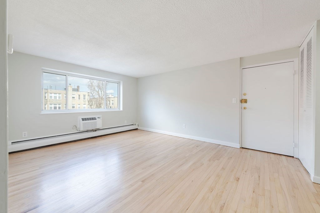 280 Corey Road, Unit 23 Boston, MA 02135 - Photo 2 of 19 an empty room with wooden floor and windows