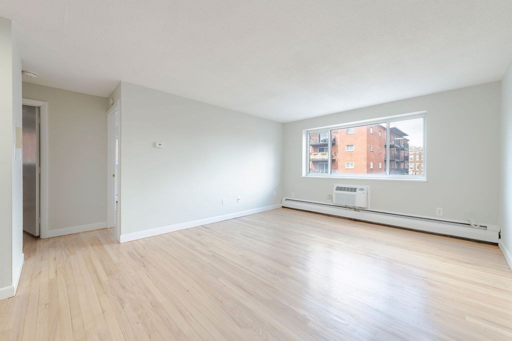280 Corey Road, Unit 23 Boston, MA 02135 - Photo 3 of 19 an empty room with wooden floor and windows
