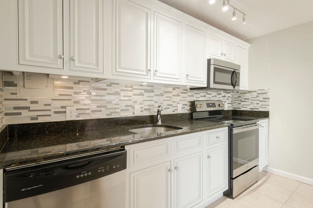 280 Corey Road, Unit 23 Boston, MA 02135 - Photo 8 of 19 a kitchen with granite countertop white cabinets and sink