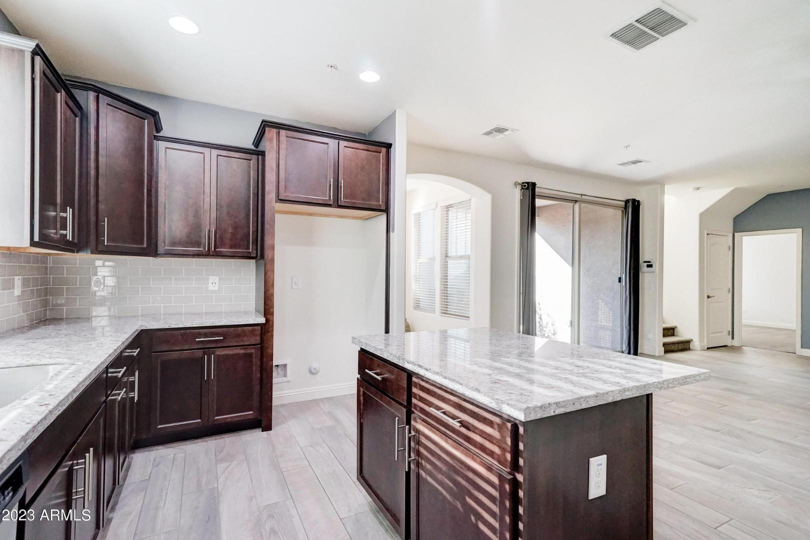 2297 North Alsap Road Buckeye, AZ 85396 - Photo 10 of 36 a kitchen with granite countertop kitchen island wooden cabinets and refrigerator