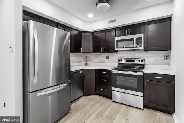 a kitchen with stainless steel appliances granite countertop a refrigerator stove a sink dishwasher and microwave