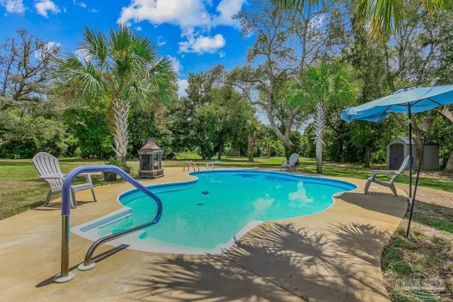 a view of a swimming pool with a patio and a yard