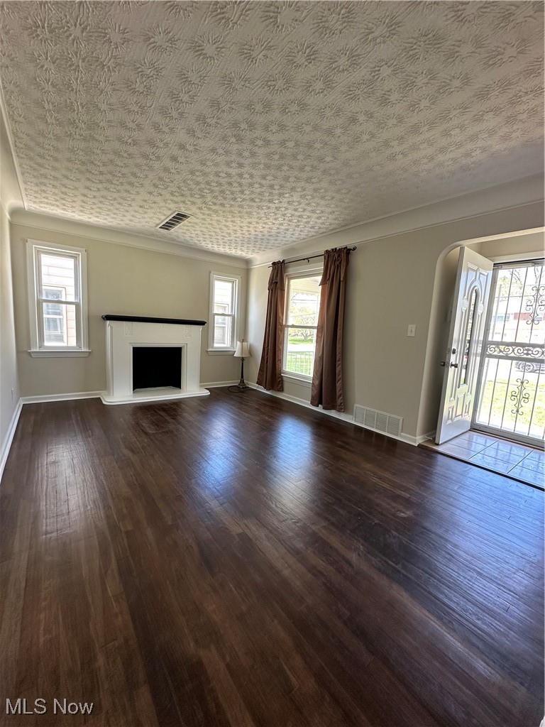 18230 Libby Road Maple Heights, OH 44137 - Photo 17 of 39 Unfurnished living room with dark wood finished floors, visible vents, arched walkways, and baseboards