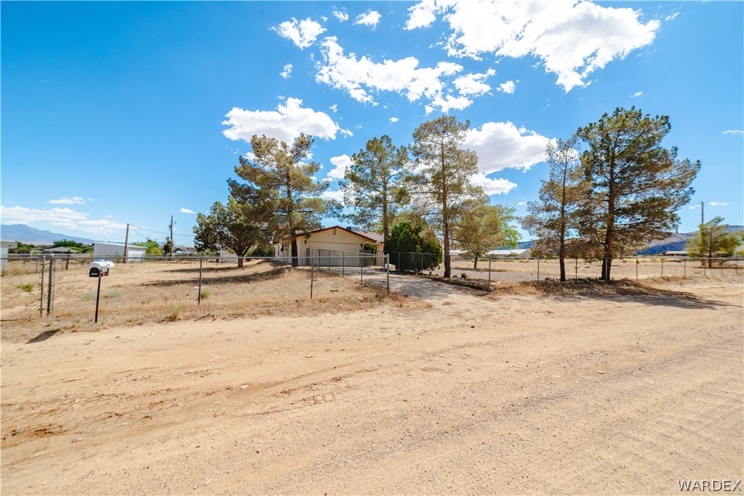 2100 East Valley View Road Kingman, AZ 86409 - Photo 52 of 53 Single-story residence featuring a neutral-toned exterior, fenced perimeter, and mature trees on a spacious parcel