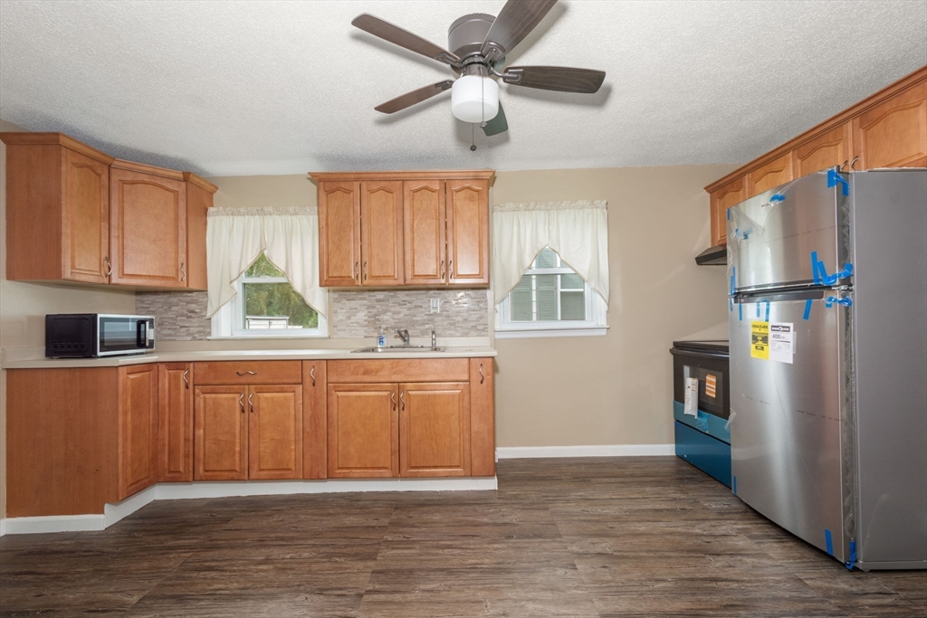 97 Mechanic Street Westfield, MA 01085 - Photo 11 of 40 a kitchen with stainless steel appliances granite countertop a refrigerator a sink dishwasher a stove and white cabinets with wooden floor