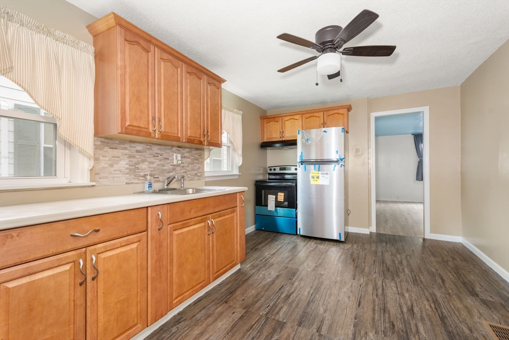 97 Mechanic Street Westfield, MA 01085 - Photo 6 of 40 a kitchen with granite countertop a refrigerator a sink a stove and white cabinets with wooden floor