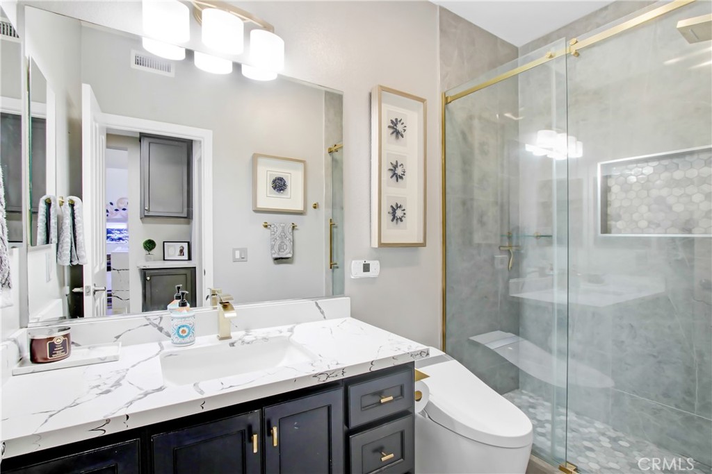 12422 Benton Drive, Unit 1 Rancho Cucamonga, CA 91739 - Photo 9 of 20 a bathroom with a granite countertop sink a toilet a mirror and shower