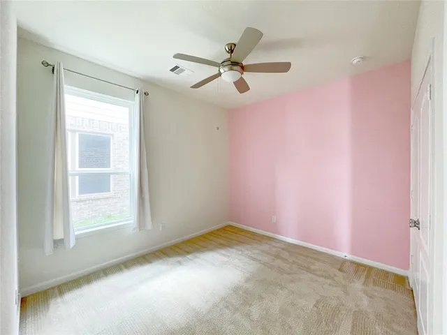 an empty room with a window and a fan