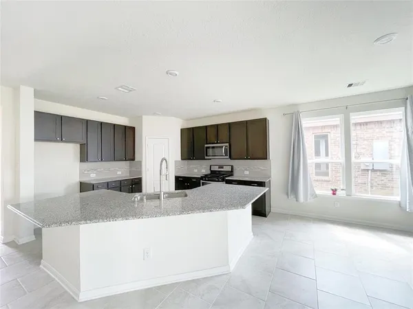 a large living room with stainless steel appliances granite countertop a couch and a flat screen tv