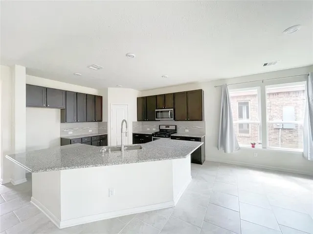 a large living room with stainless steel appliances granite countertop a couch and a flat screen tv