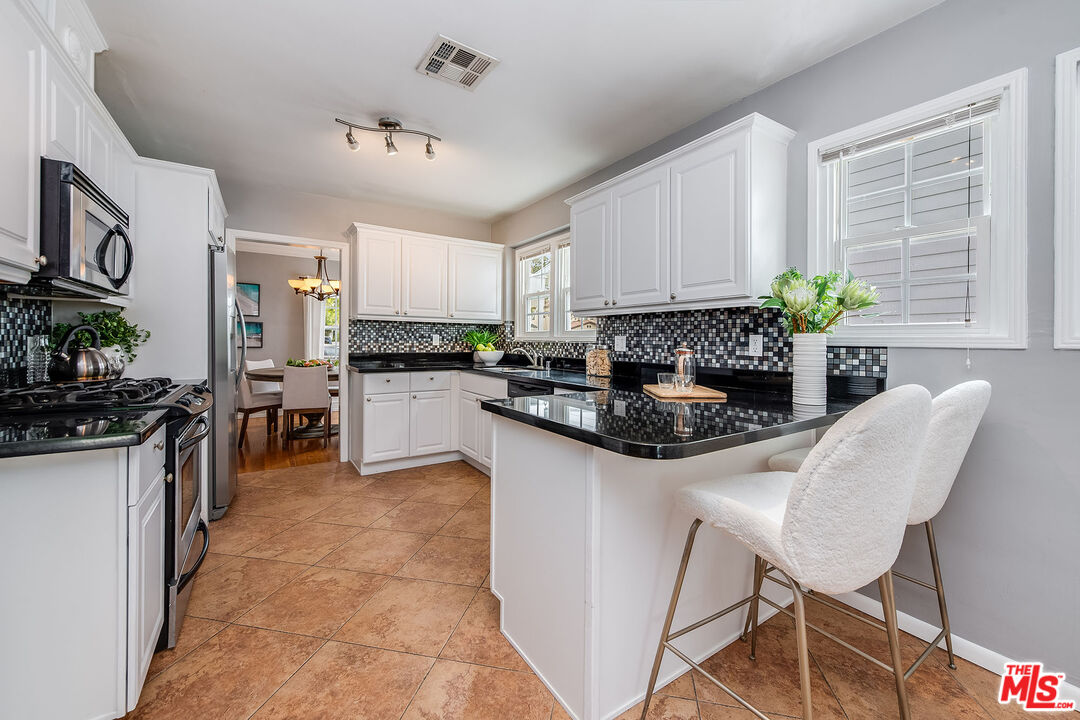 4539 Atoll Avenue Sherman Oaks, CA 91423 - Photo 10 of 28 a kitchen with stainless steel appliances granite countertop a refrigerator a stove a sink dishwasher and white cabinets with wooden floor
