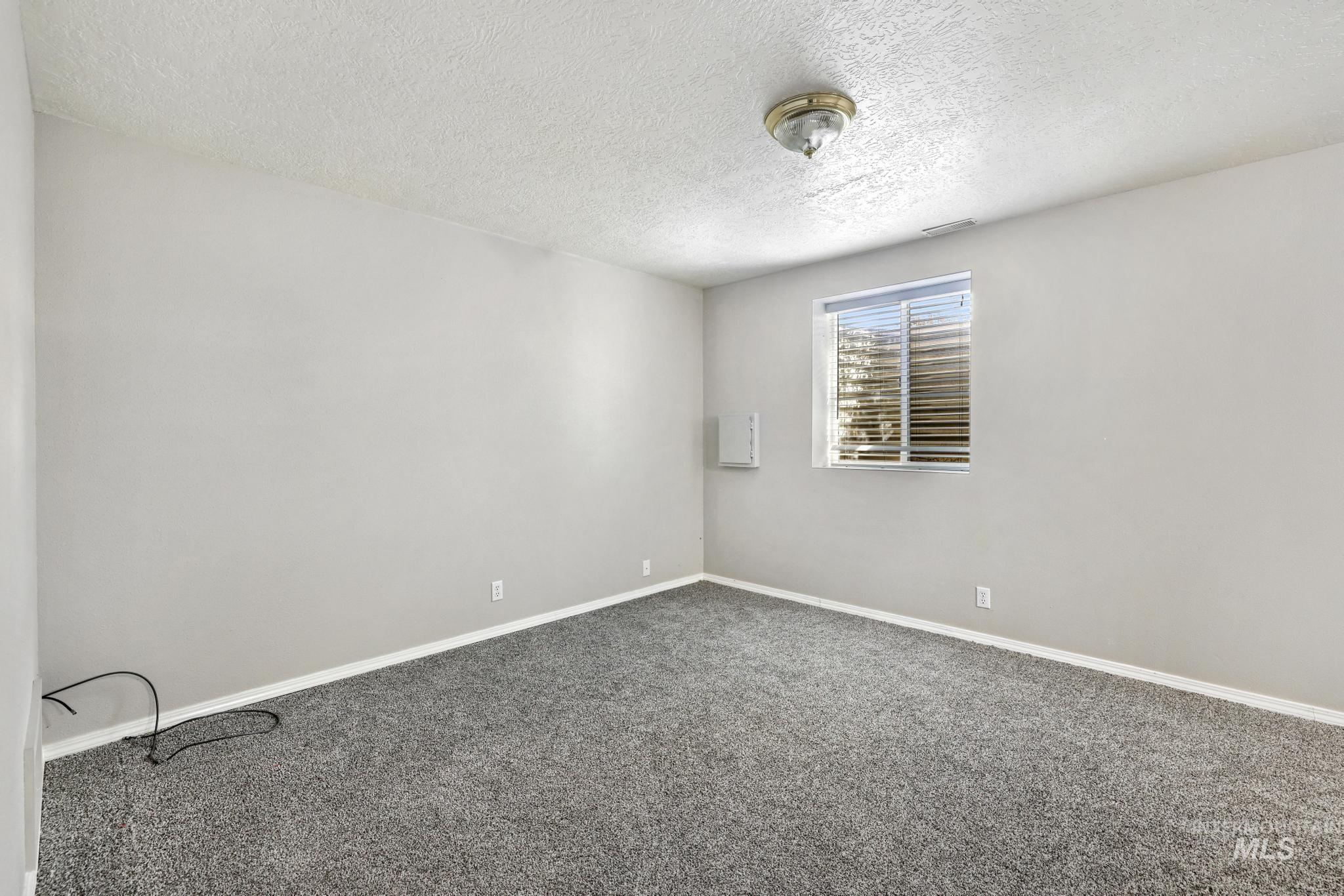 445 South College Street Oakley, ID 83346 - Photo 13 of 24 Spare room featuring dark carpet and a textured ceiling