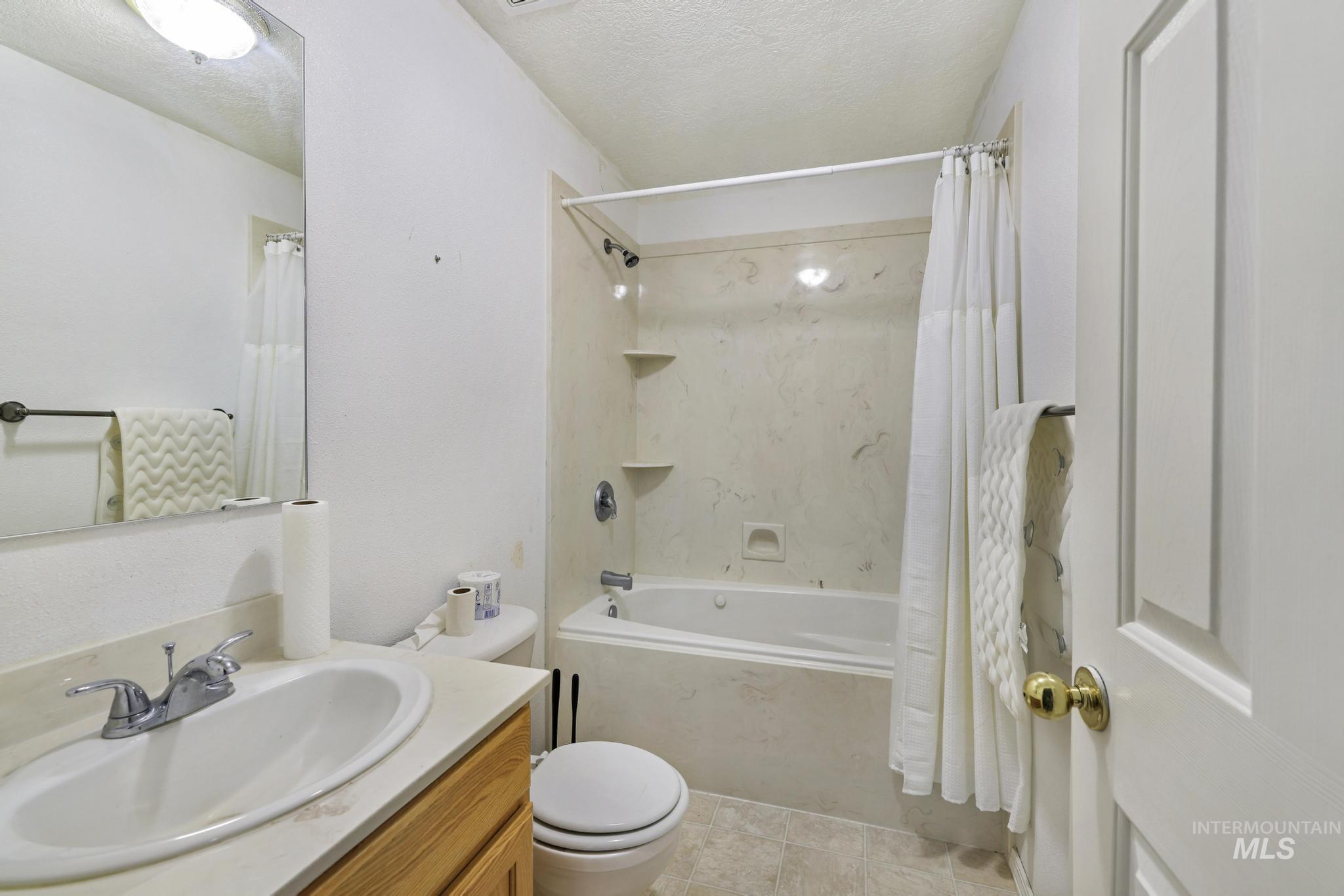 445 South College Street Oakley, ID 83346 - Photo 14 of 24 Bathroom with vanity, a textured ceiling, shower / bathtub combination with curtain, and light tile patterned floors