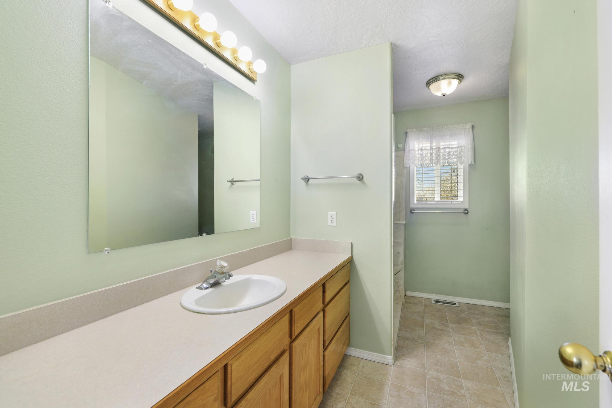 445 South College Street Oakley, ID 83346 - Photo 16 of 24 Full bath featuring a stall shower, vanity, a textured ceiling, and light tile patterned flooring