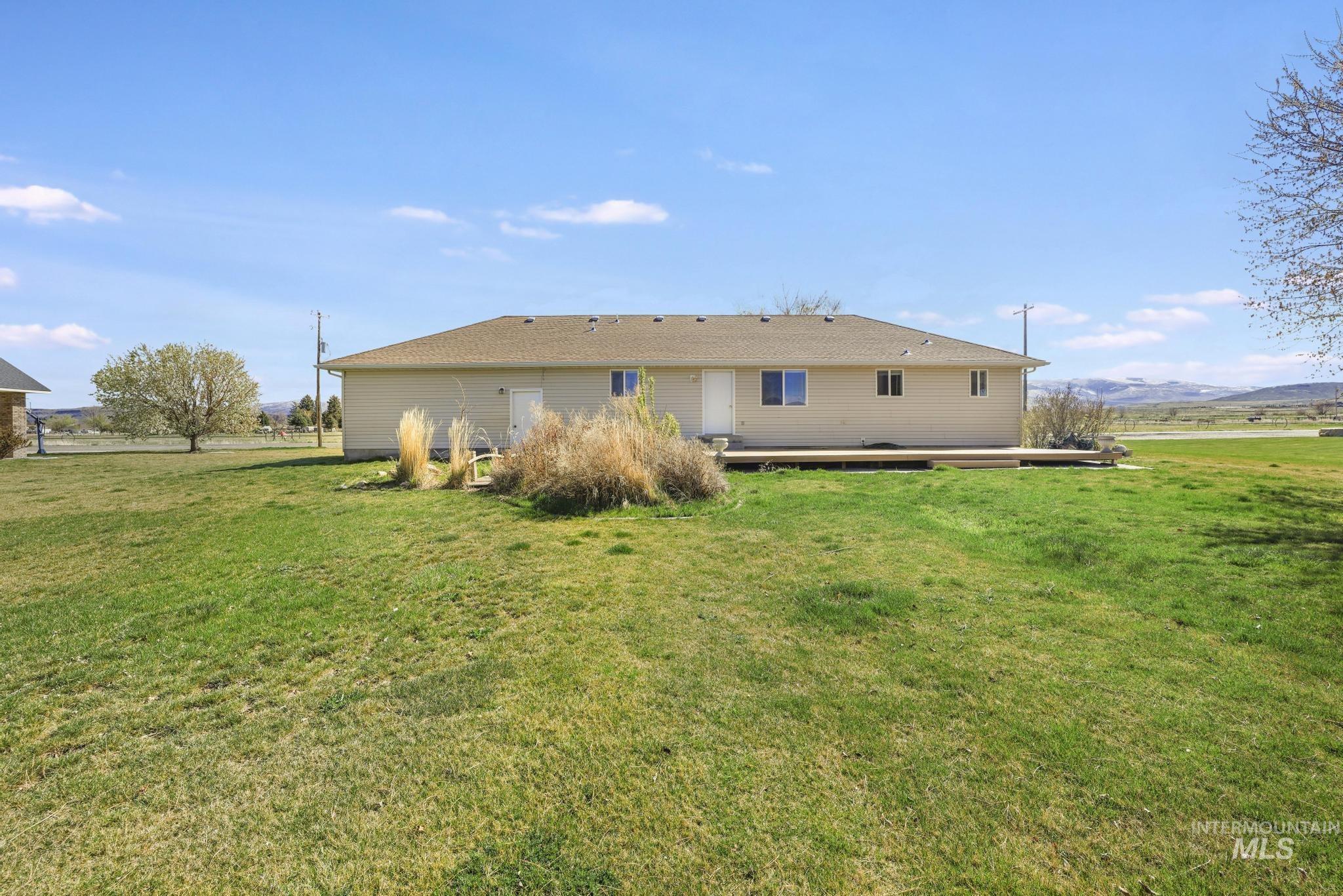 445 South College Street Oakley, ID 83346 - Photo 18 of 24 Rear view of property featuring a mountain view, a lawn, and a patio area
