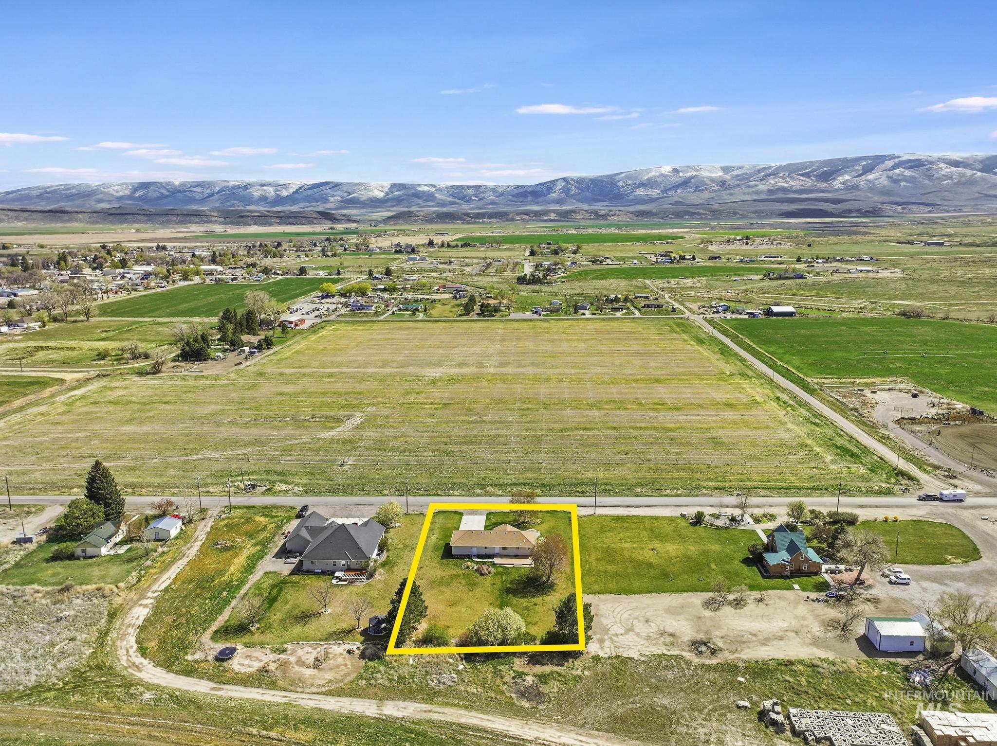 445 South College Street Oakley, ID 83346 - Photo 22 of 24 Aerial view of sparsely populated area featuring property parcel outlined, a mountain backdrop, and rows of crops
