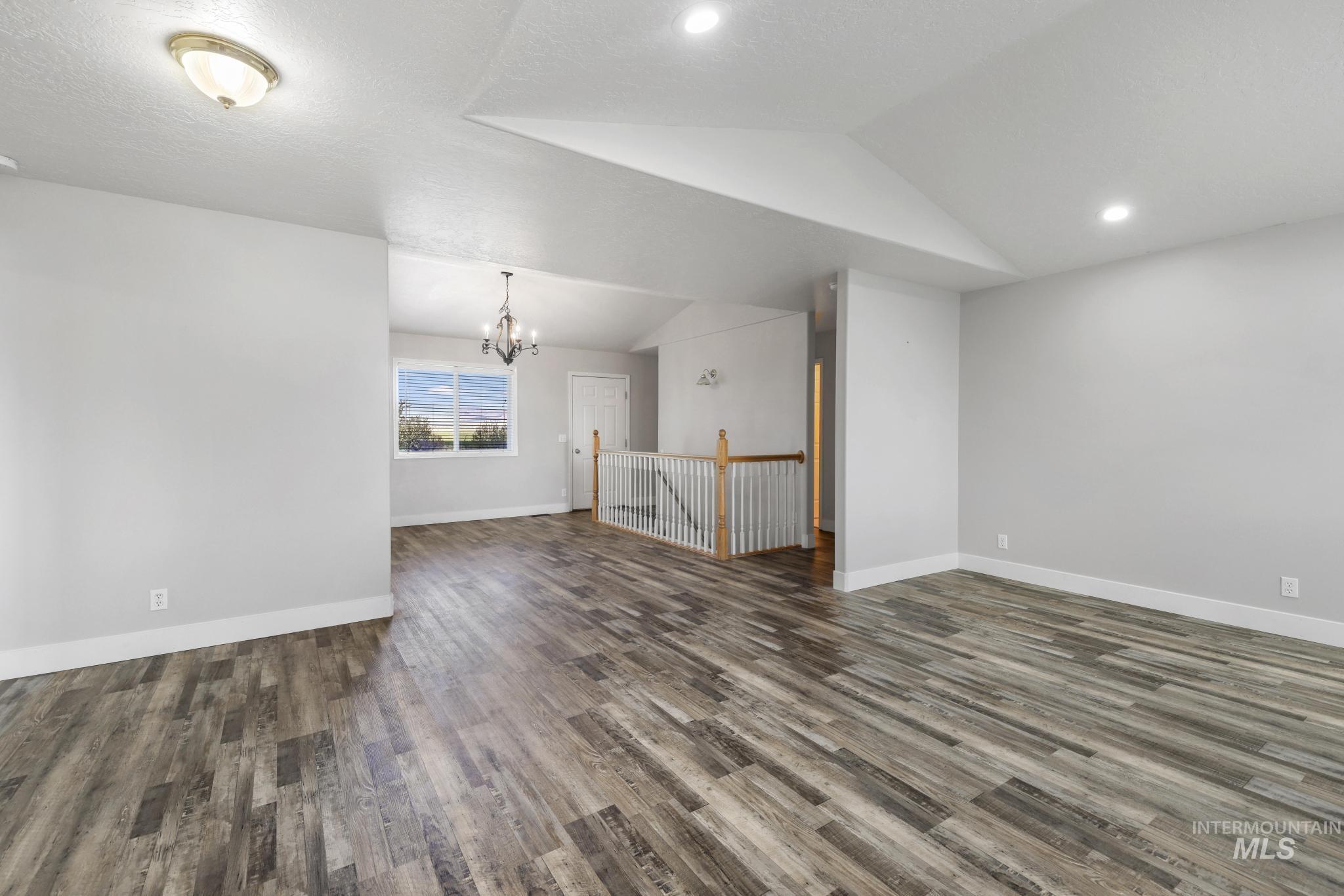 445 South College Street Oakley, ID 83346 - Photo 3 of 24 Spare room featuring vaulted ceiling, dark wood-type flooring, and a chandelier