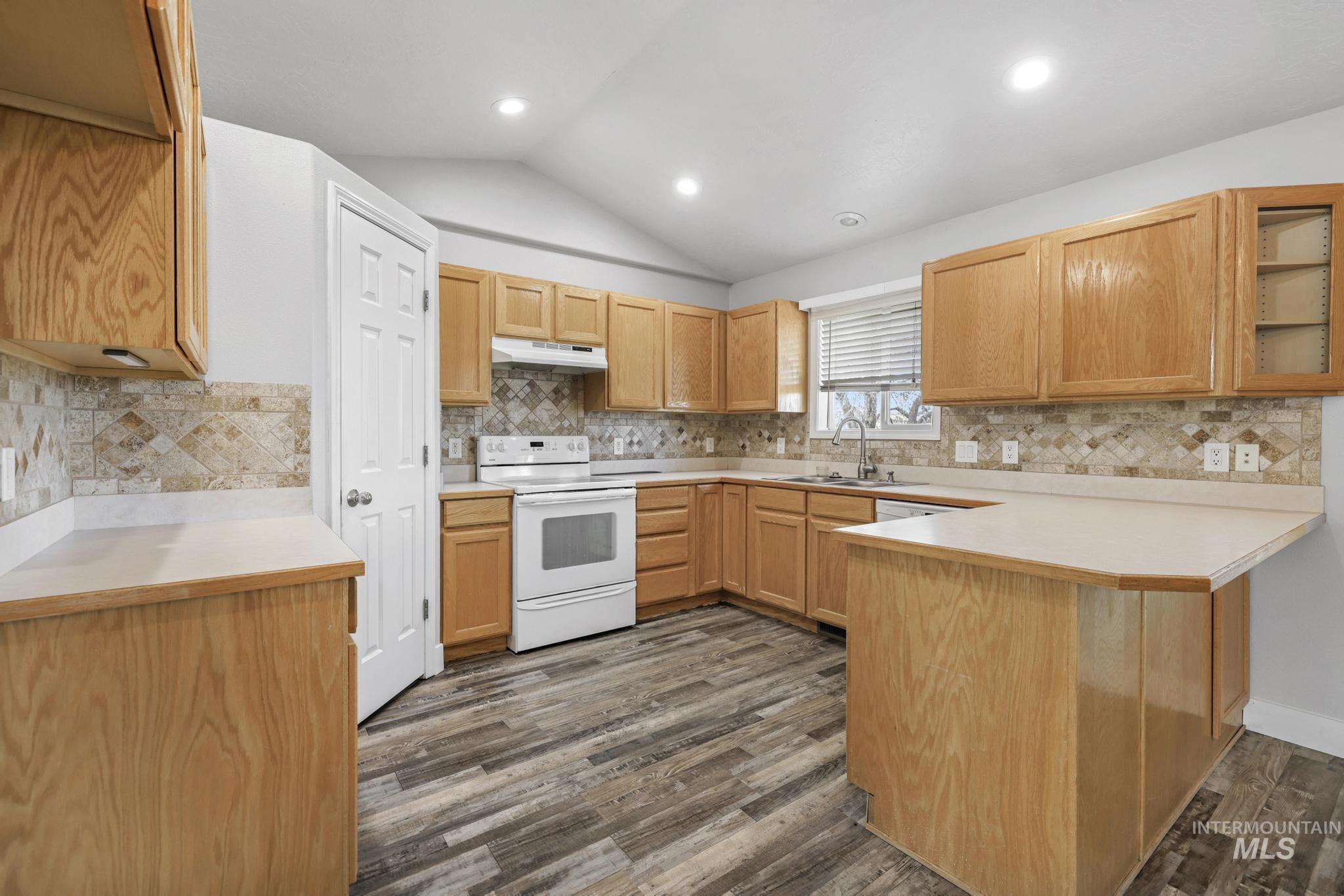 445 South College Street Oakley, ID 83346 - Photo 5 of 24 Kitchen featuring a peninsula, light countertops, white electric stove, vaulted ceiling, and dark wood finished floors