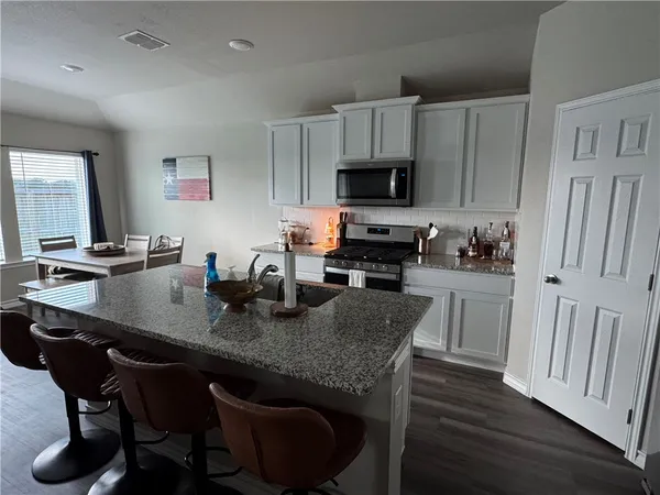 a kitchen with stainless steel appliances granite countertop a table chairs sink refrigerator and cabinets
