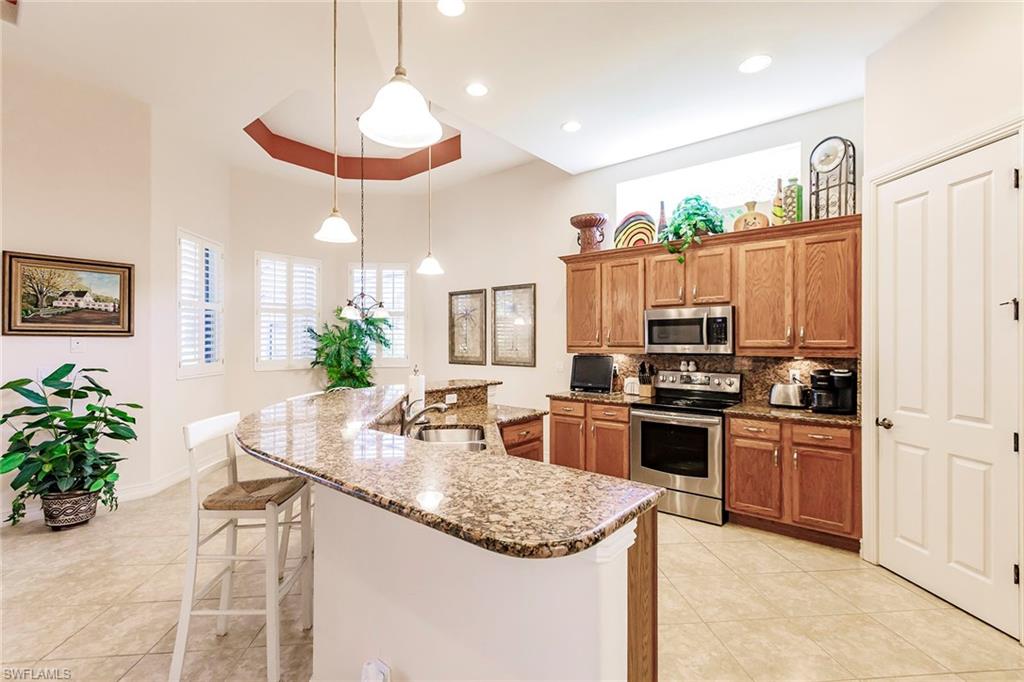 7684 Cottesmore Drive Naples, FL 34113 - Photo 11 of 46 a kitchen with stainless steel appliances granite countertop a sink stove and refrigerator
