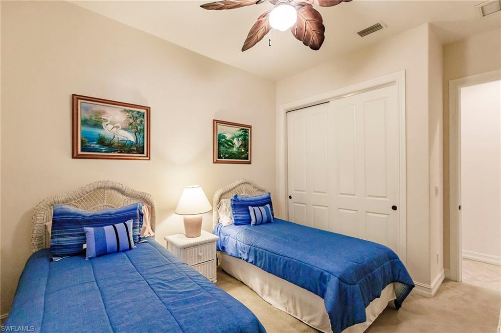 7684 Cottesmore Drive Naples, FL 34113 - Photo 41 of 46 a spacious bedroom with a bed and lamp painting on the wall