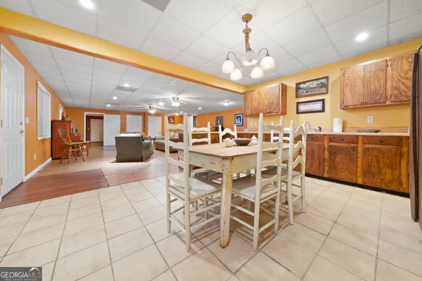 a dining area with stainless steel appliances kitchen island granite countertop a table chairs and a chandelier