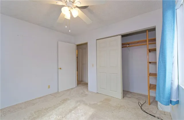 an empty room with closet and a chandelier fan