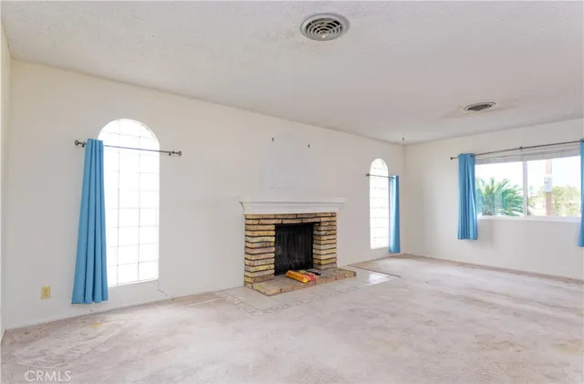 an empty room with windows and fireplace