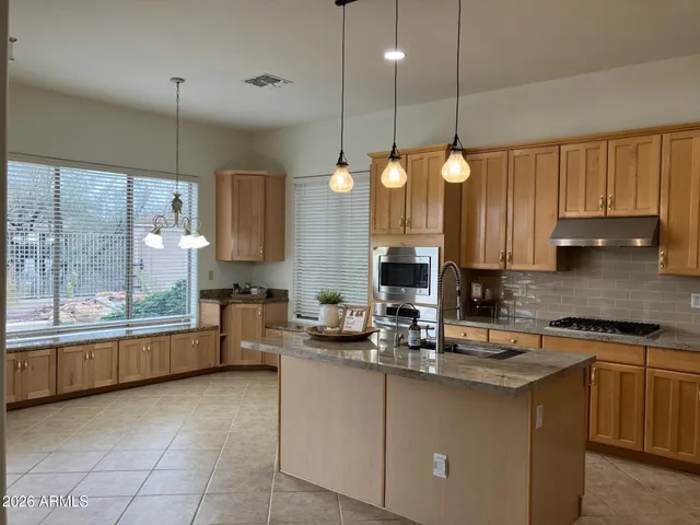 a kitchen with kitchen island granite countertop a stove a sink and a cabinets