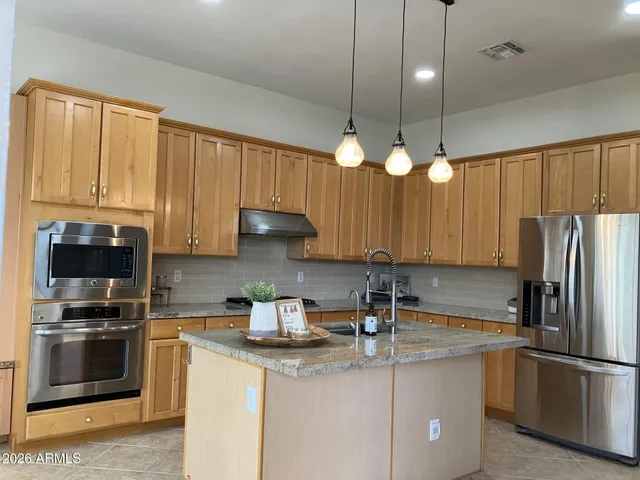 a kitchen with stainless steel appliances granite countertop a sink a stove and a refrigerator