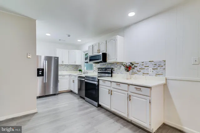 a kitchen with white cabinets and stainless steel appliances