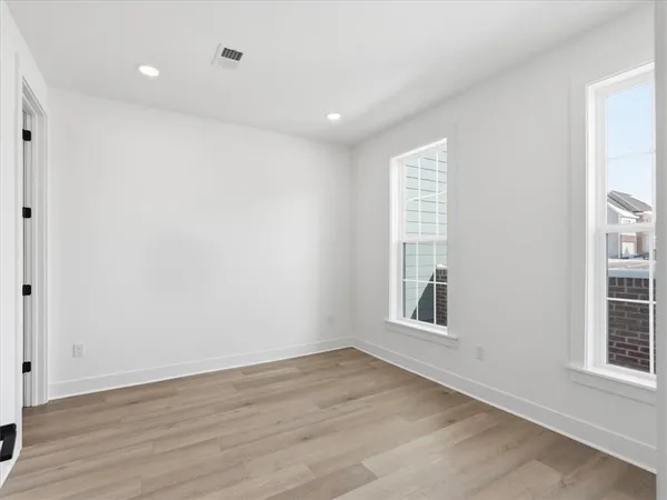 a view of an empty room with wooden floor and windows