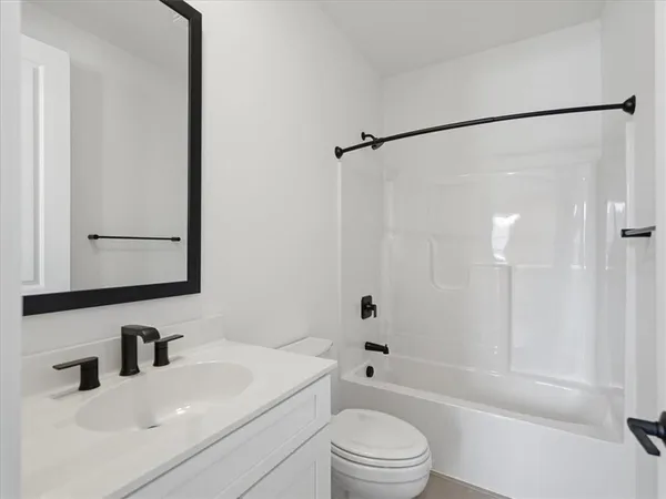 a bathroom with a bathtub shower sink vanity and toilet